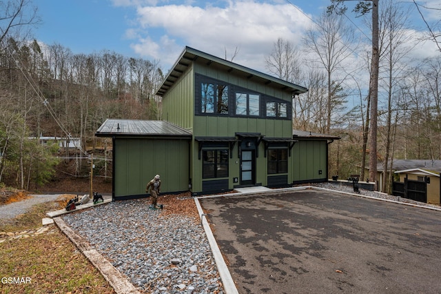 view of front of home featuring metal roof, board and batten siding, and driveway