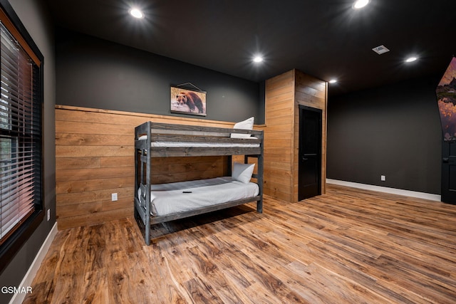 bedroom featuring wainscoting, wooden walls, wood finished floors, and recessed lighting