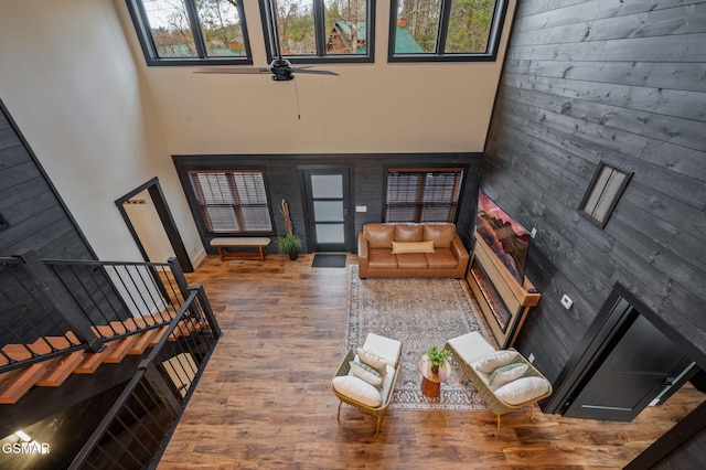 living area with stairs, a high ceiling, plenty of natural light, and wood finished floors