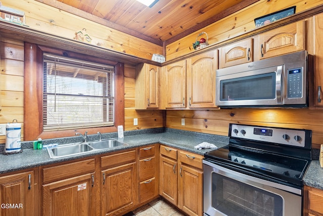 kitchen with wooden walls, stainless steel appliances, and a sink