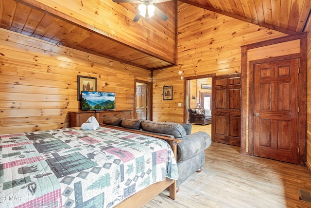 bedroom with light hardwood / wood-style floors, ceiling fan, and wood walls