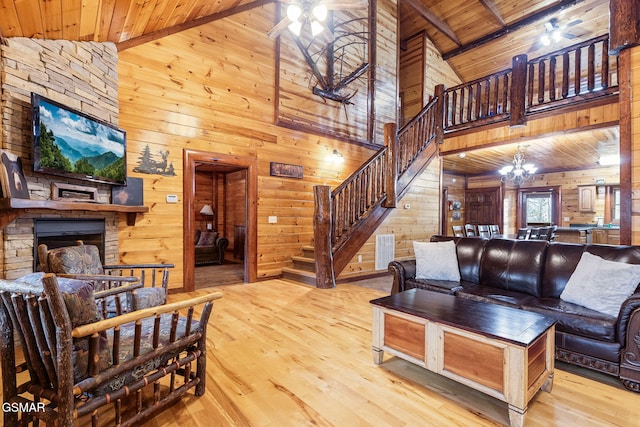 living area with wooden ceiling, a stone fireplace, wood walls, and an inviting chandelier