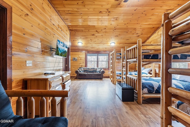 bedroom with light wood-type flooring, vaulted ceiling, wooden ceiling, and wood walls