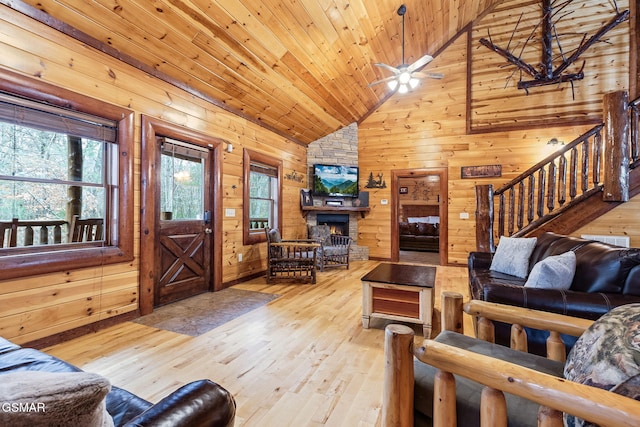 living room featuring wood walls, wooden ceiling, high vaulted ceiling, light hardwood / wood-style flooring, and a fireplace