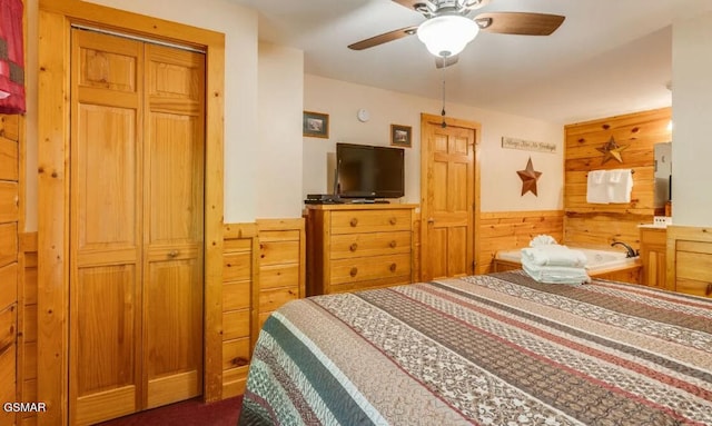 carpeted bedroom with ceiling fan, a closet, and wood walls