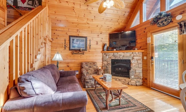 living room with wood-type flooring, a fireplace, ceiling fan, wooden walls, and high vaulted ceiling