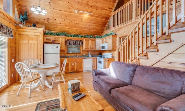 living room with high vaulted ceiling, sink, light hardwood / wood-style flooring, and wooden walls