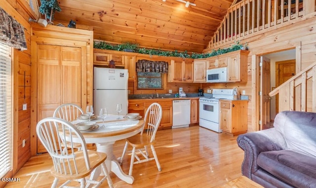 kitchen featuring light brown cabinetry, white appliances, wood walls, and light wood-type flooring