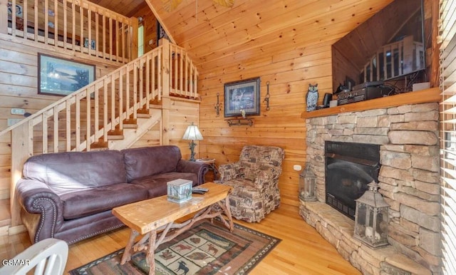 living room with hardwood / wood-style flooring, wooden ceiling, a stone fireplace, and vaulted ceiling