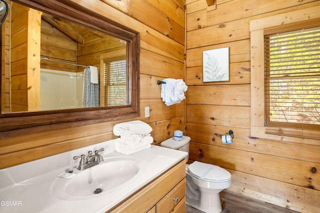 bathroom with wood walls, plenty of natural light, curtained shower, and vanity