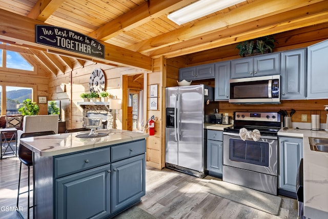 kitchen featuring lofted ceiling with beams, wooden ceiling, stainless steel appliances, wood walls, and light wood-type flooring