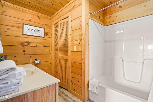 full bath with wooden ceiling, wood finished floors, vanity, and wooden walls