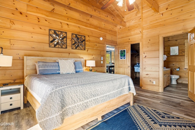 bedroom featuring lofted ceiling with beams, wood walls, and wood finished floors