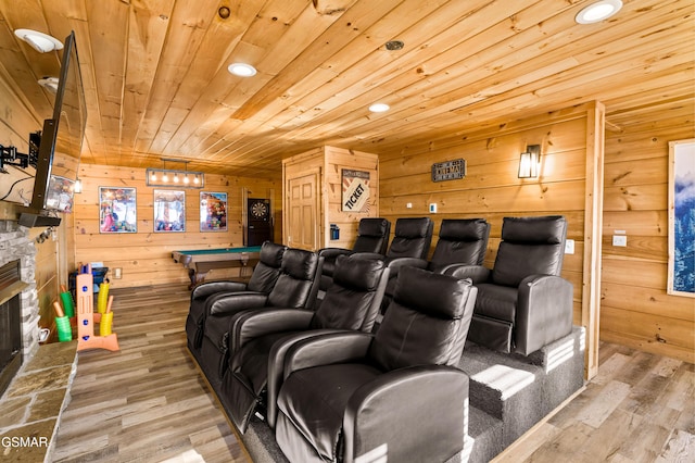 cinema room featuring wooden ceiling, wood finished floors, a stone fireplace, wood walls, and recessed lighting