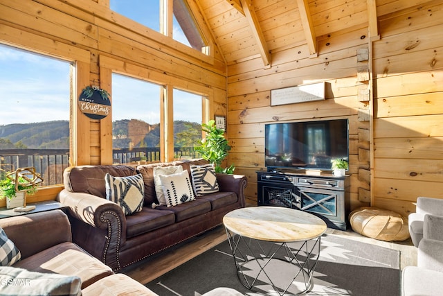 living area with lofted ceiling with beams, wood walls, wooden ceiling, and a wealth of natural light