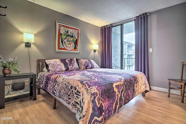 bedroom with baseboards, floor to ceiling windows, wood finished floors, and a textured ceiling