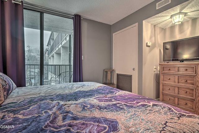 bedroom with a textured ceiling, access to outside, and visible vents