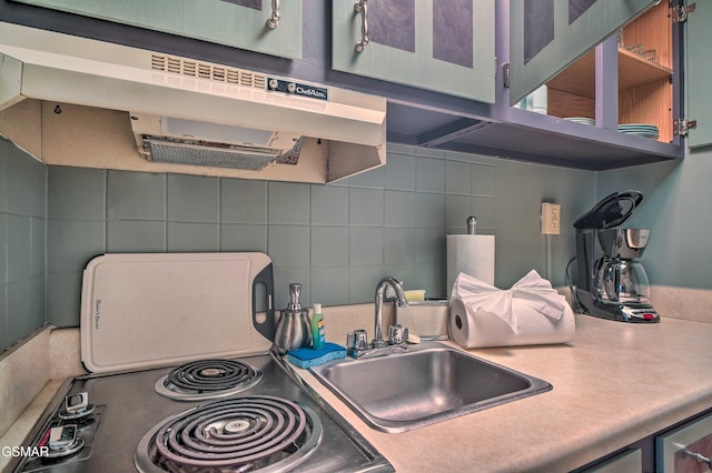 kitchen with backsplash, light countertops, a sink, and under cabinet range hood