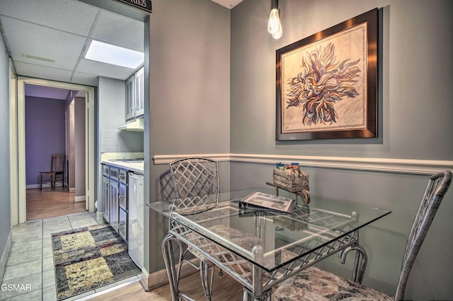 dining room featuring baseboards, light wood-type flooring, visible vents, and a paneled ceiling