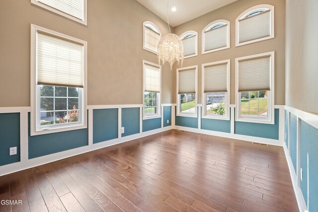 empty room featuring hardwood / wood-style floors, a high ceiling, and a chandelier