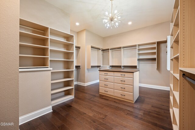 walk in closet featuring an inviting chandelier and dark wood-type flooring