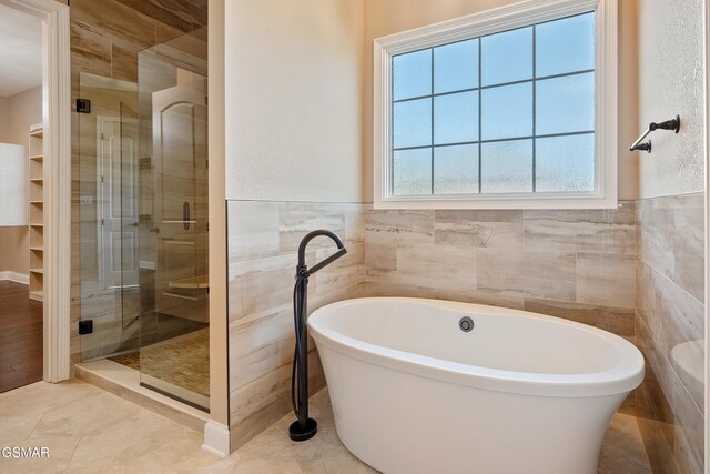 bathroom featuring tile patterned flooring, tile walls, and independent shower and bath