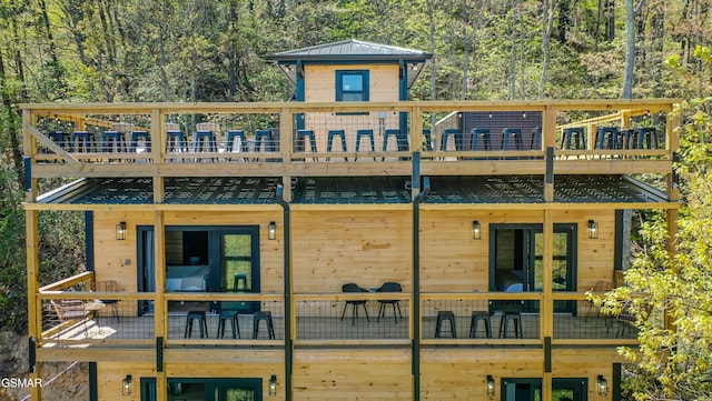 back of house featuring a forest view and a deck