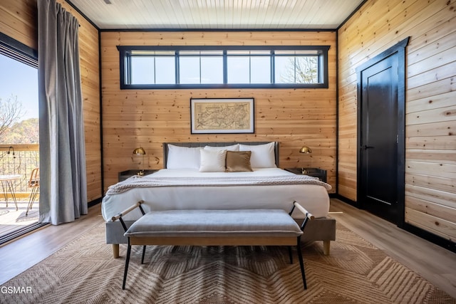 bedroom featuring multiple windows, wood finished floors, and wood walls