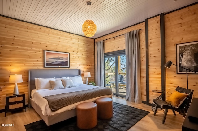 bedroom featuring wood finished floors, wooden walls, access to exterior, and wooden ceiling