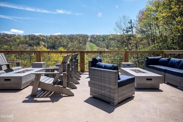 view of patio / terrace with an outdoor living space with a fire pit and a view of trees