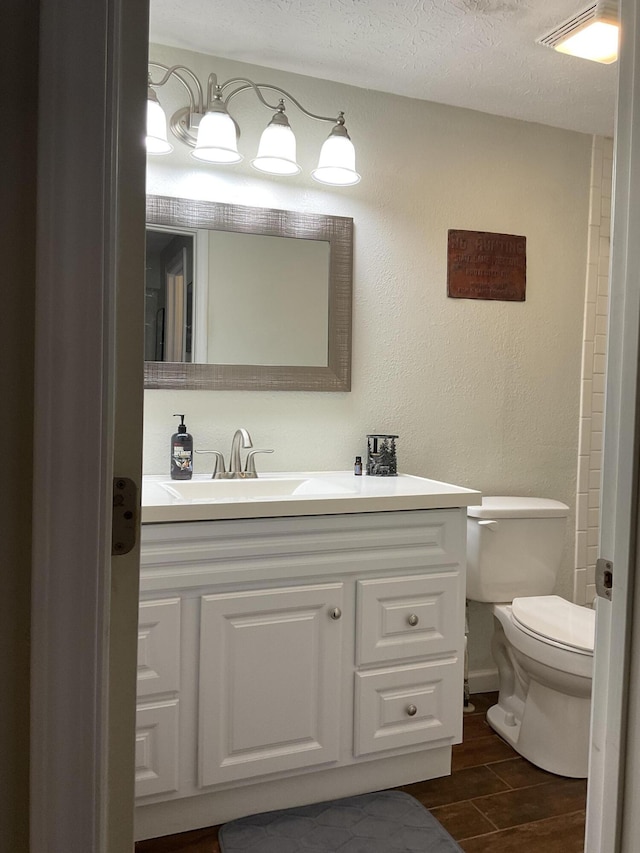 bathroom featuring vanity, a textured ceiling, and toilet