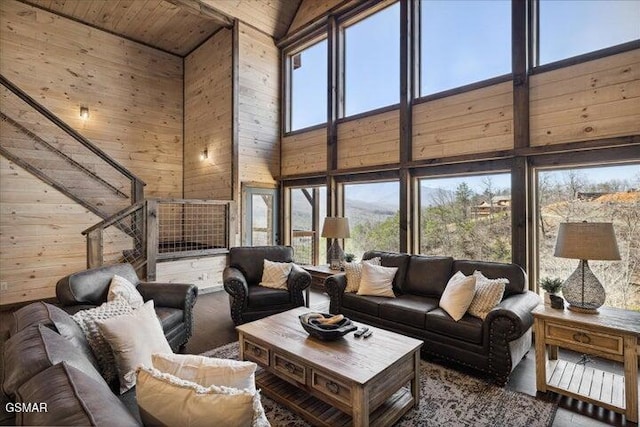 living area with a healthy amount of sunlight, high vaulted ceiling, and wood walls