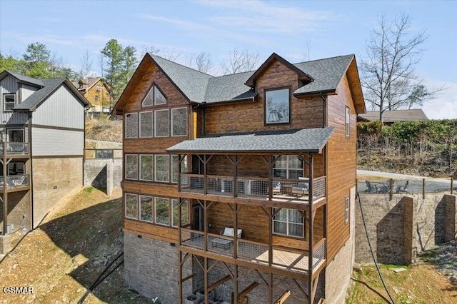 back of property with roof with shingles and a balcony