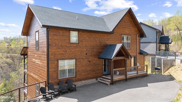 back of property featuring a patio area and roof with shingles