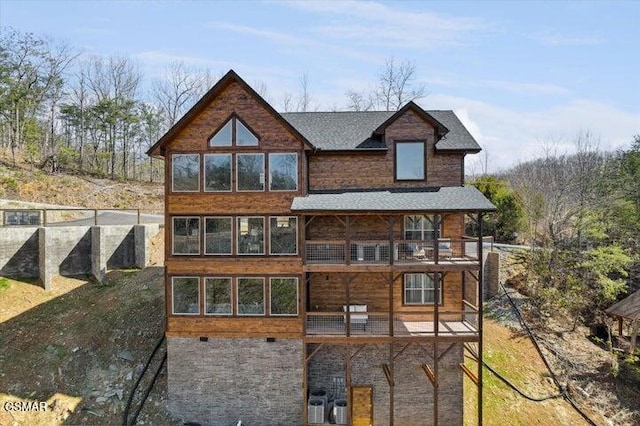 back of house featuring roof with shingles, a balcony, and cooling unit