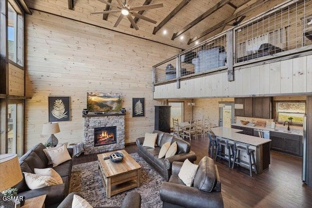 living room featuring dark wood-style flooring, beam ceiling, high vaulted ceiling, a ceiling fan, and wooden ceiling