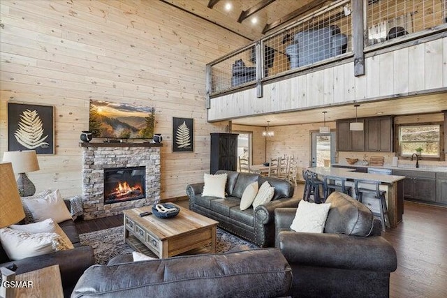 living room featuring wooden walls, a high ceiling, a fireplace, and dark wood finished floors