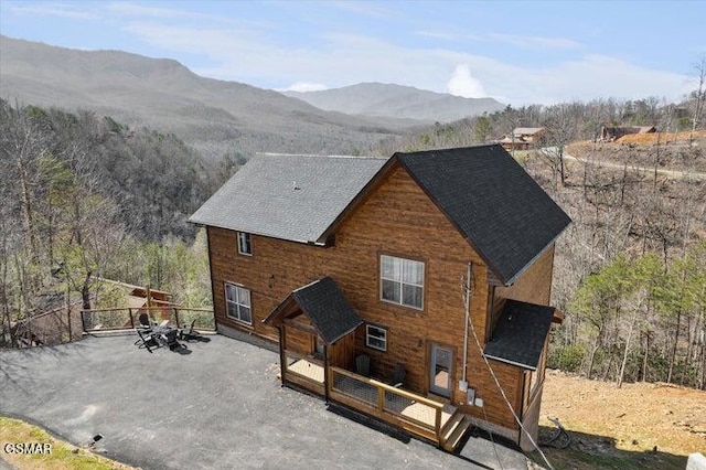 back of house featuring a shingled roof and a deck with mountain view
