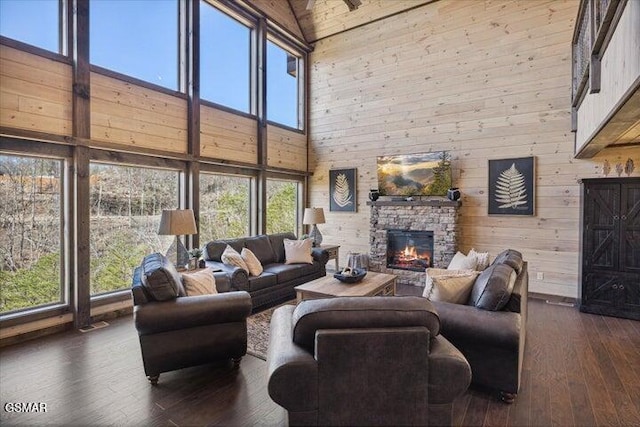 living area featuring wooden walls, dark wood-style flooring, high vaulted ceiling, and a fireplace