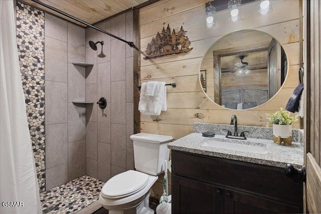 bathroom featuring toilet, wood walls, tiled shower, and vanity