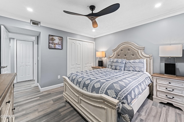 bedroom featuring ceiling fan, ornamental molding, wood-type flooring, and a closet