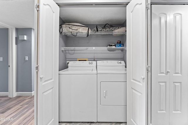 laundry room with washing machine and dryer and light hardwood / wood-style flooring