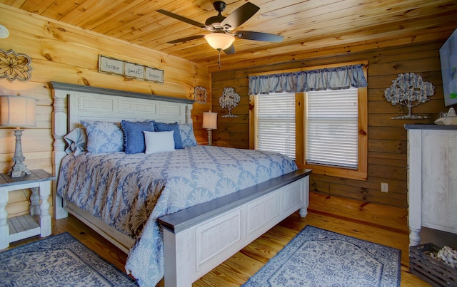 bedroom with ceiling fan, wood walls, light wood-type flooring, and wooden ceiling