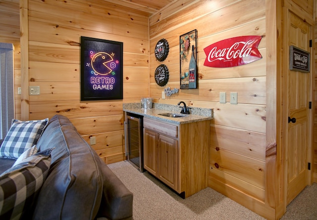 bar featuring light colored carpet, sink, and wooden walls