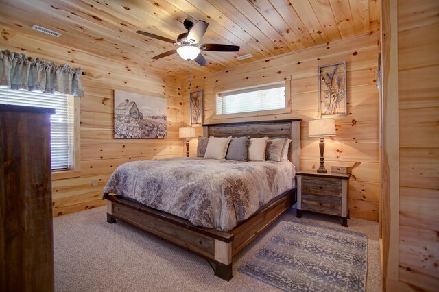 carpeted bedroom with ceiling fan, wooden ceiling, wooden walls, and multiple windows