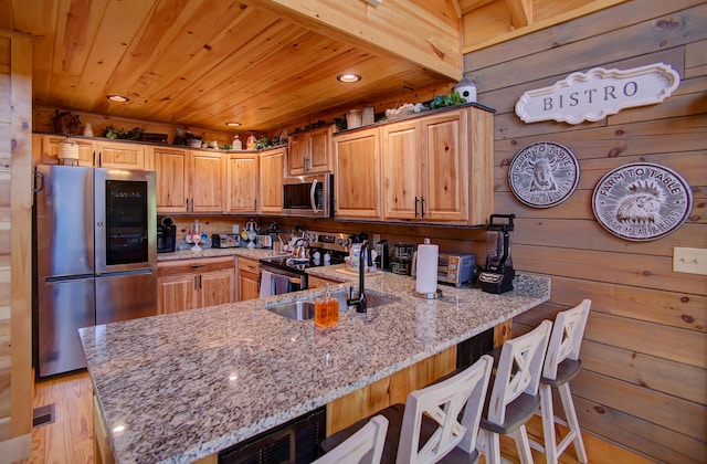 kitchen featuring stainless steel appliances, light stone counters, wood walls, light hardwood / wood-style floors, and wood ceiling