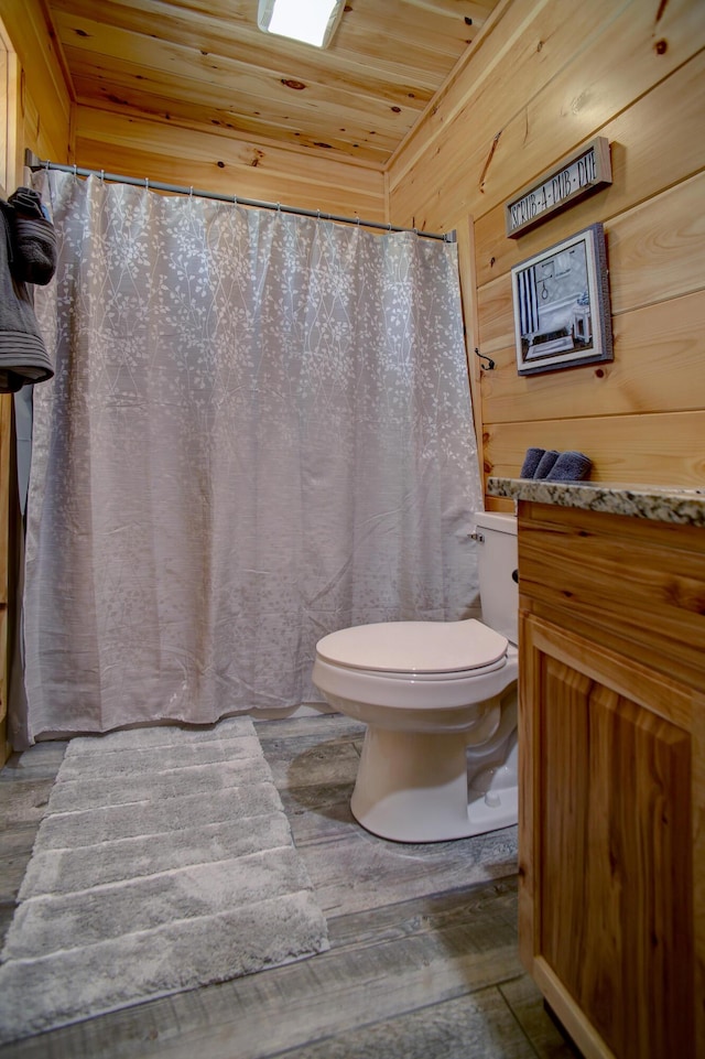 bathroom with wood walls, hardwood / wood-style floors, wooden ceiling, and toilet