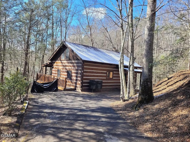 view of outdoor structure with driveway and a view of trees