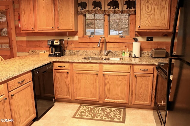 kitchen with range, a sink, light stone counters, freestanding refrigerator, and black dishwasher