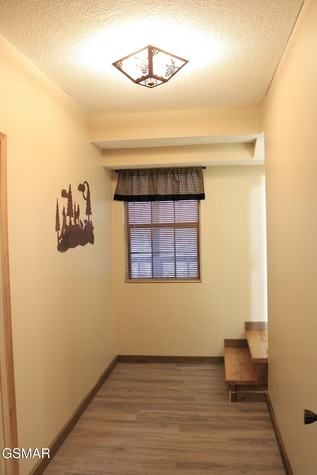 spare room featuring baseboards, a textured ceiling, and wood finished floors